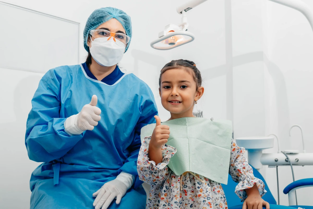 Pediatric dentist with a kid posing after dental cleaning